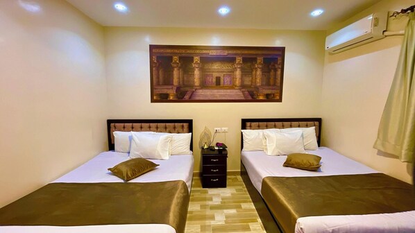 Une chambre d’hôtel avec deux lits, une table de chevet, un climatiseur fixé au mur et un tableau encadré au-dessus des lits.