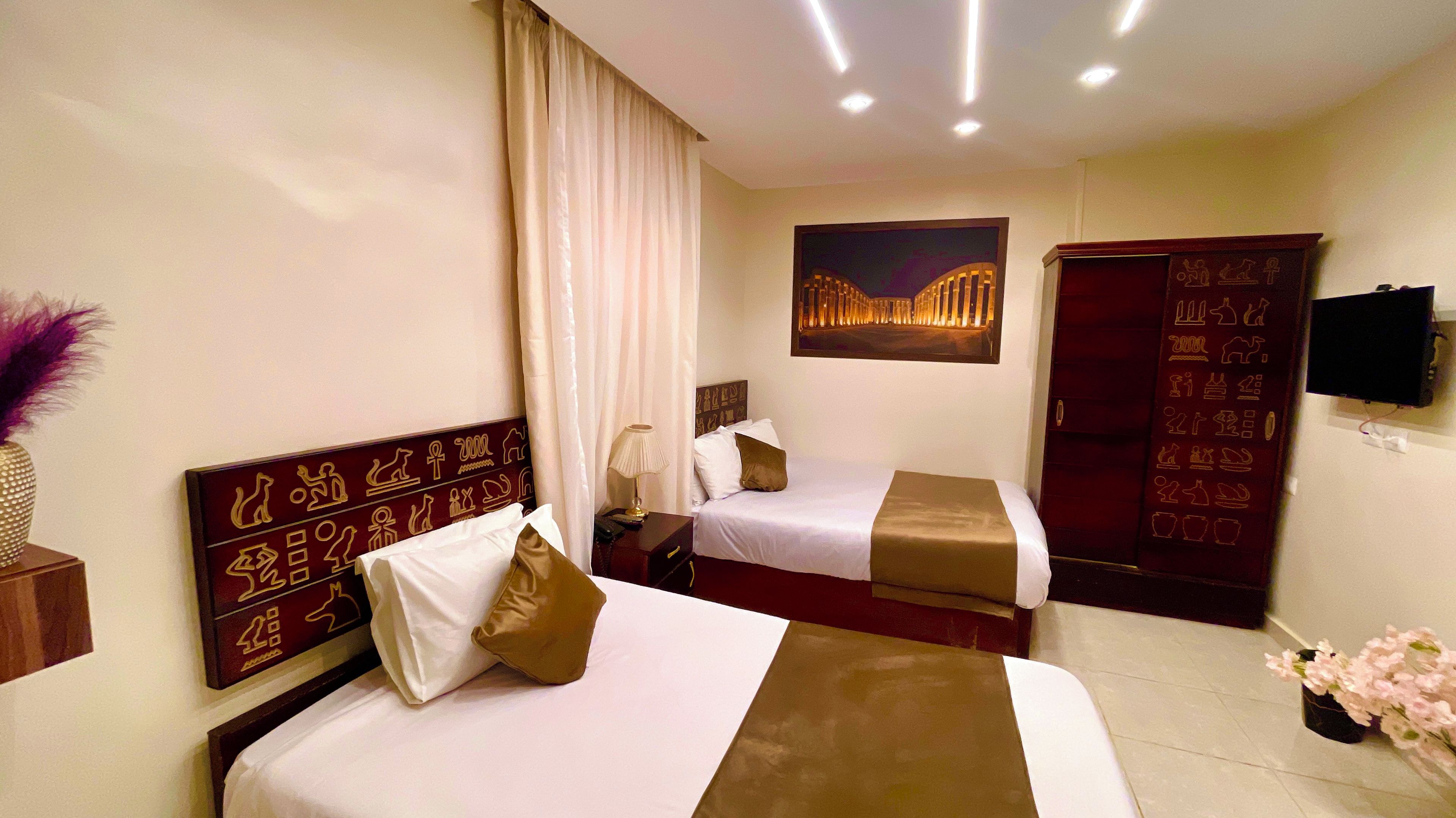Una habitación de hotel con dos camas, televisión, un cuadro y un armario.