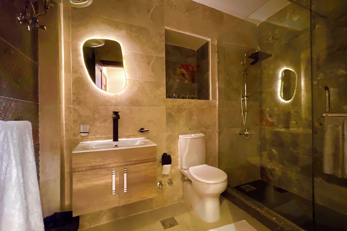 A modern bathroom with a glass-enclosed shower, a vanity with a mirror, and a toilet.