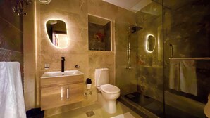 Un baño moderno con ducha envuelta en vidrio, tocador con espejo y un inodoro.