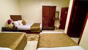 Una habitación de hotel con dos camas, un armario de madera, una mesita de noche y un espejo.