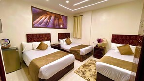A hotel room with three beds, a large wall mural, a minibar, and a decorative rug. - Nemes Pyramids View Inn (Giza)
