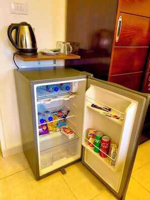 Un refrigerador compacto con un compartimento congelador pequeño, una repisa y un tirador de puerta.