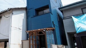 A blue building with a wooden structure in front, possibly a gate or entrance. - Core Base Sumiyoshi (Fukuoka)