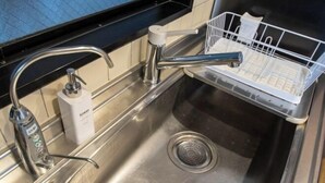 A stainless steel kitchen sink with a modern faucet, a soap dispenser, and a dish drying rack. - Core Base Sumiyoshi (Fukuoka)