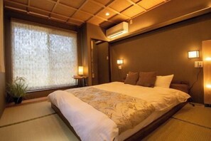 Une chambre d’hôtel avec un grand lit, un ventilateur de plafond, un appareil de climatisation et une fenêtre avec des rideaux.