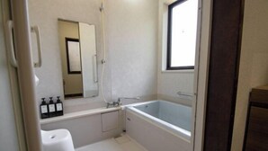 A bathroom with a bathtub, a toilet, a sink, and a window. - Core Base Sumiyoshi (Fukuoka)