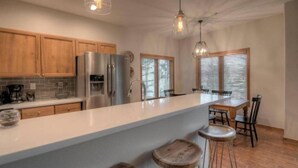 Une cuisine moderne avec des meubles en bois, des appareils en acier inoxydable et un grand îlot central doté de tabourets.