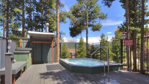 Une terrasse en bois avec un jacuzzi, un espace salon couvert et une piscine clôturée.