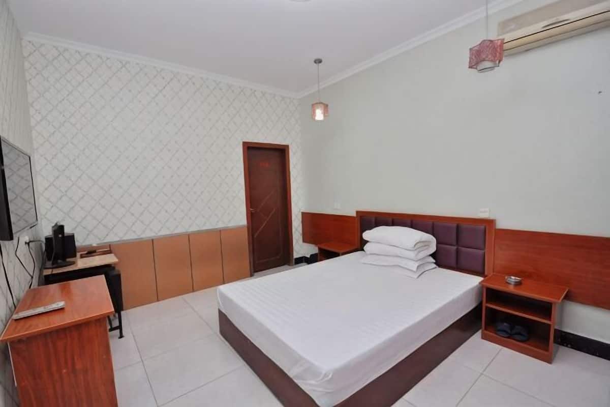 Une chambre à coucher comprenant un lit, un bureau, une chaise, une télévision et une armoire.