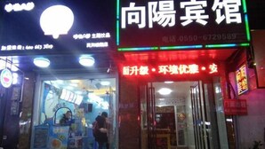 A brightly lit storefront with a neon sign and a glass display window. - Fengyang Xiangyang Hotel (Fengyang)