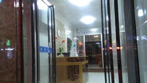 A hotel lobby with a reception desk, a clock on the wall, and a decorative wall panel. - Fengyang Xiangyang Hotel (Fengyang)