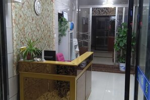 A reception area with a reception desk, a clock, and potted plants.