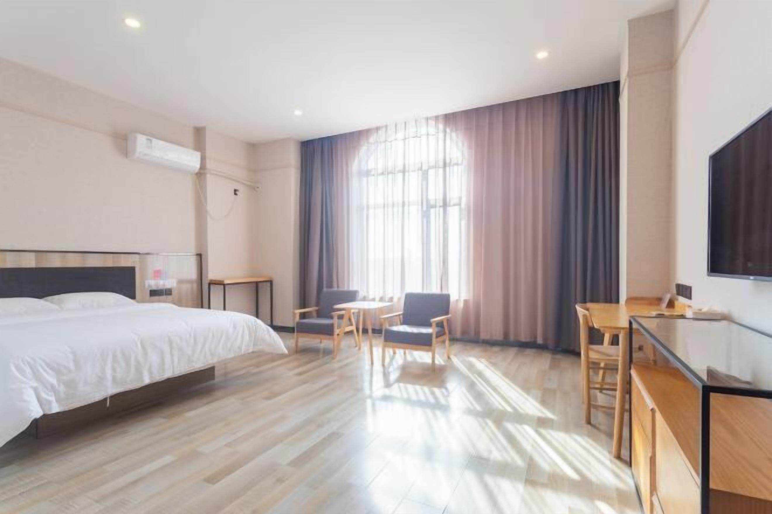 A hotel room with a bed, a desk, a chair, and a TV.