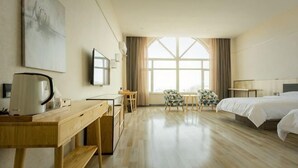 A hotel room with a bed, a desk, a chair, a coffee maker, and a large window. - Shankee Tea Style Hotel (Qingdao Jiaodong International Airport Haier Avenue) (Jiaozhou)