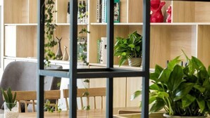 A room with a wooden dining table, chairs, a bookshelf with books and decorative items, and potted plants. - Shankee Tea Style Hotel (Qingdao Jiaodong International Airport Haier Avenue) (Jiaozhou)