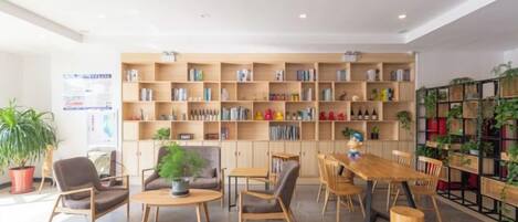 Una habitación amplia con una gran mesa de madera y sillas, rodeada de estanterías llenas de libros y adornos.