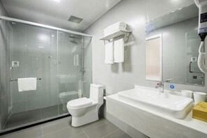 A modern bathroom with a glass-enclosed shower, a white toilet, a large bathtub, and a mirror with a towel rack.