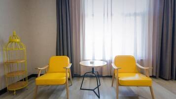 A room with two yellow chairs, a small round table, and a yellow metal shelf unit.