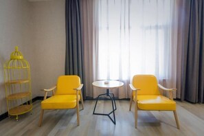 Une pièce avec deux chaises jaunes, une petite table ronde et une étagère métallique jaune.