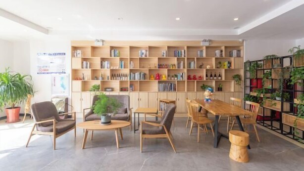 A modern library with wooden bookshelves, comfortable seating, and potted plants. - Shankee Tea Style Hotel (Qingdao Jiaodong International Airport Haier Avenue) (Jiaozhou)