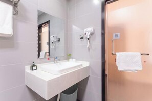 Une salle de bain moderne avec un lavabo blanc, un miroir, un sèche-cheveux et un porte-serviettes.
