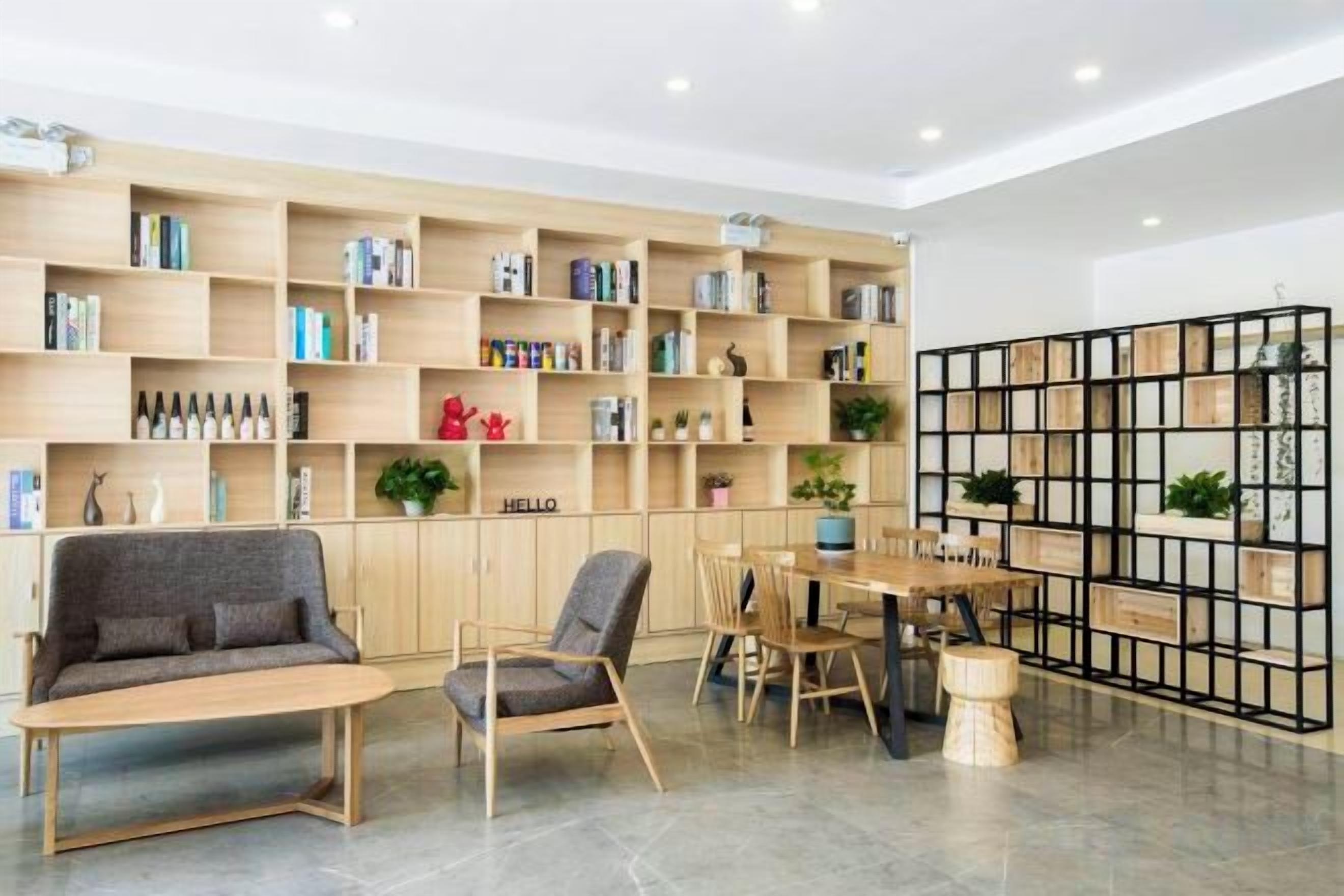 A modern living room with a sofa, chairs, a coffee table, and a bookshelf filled with books and decorative items.