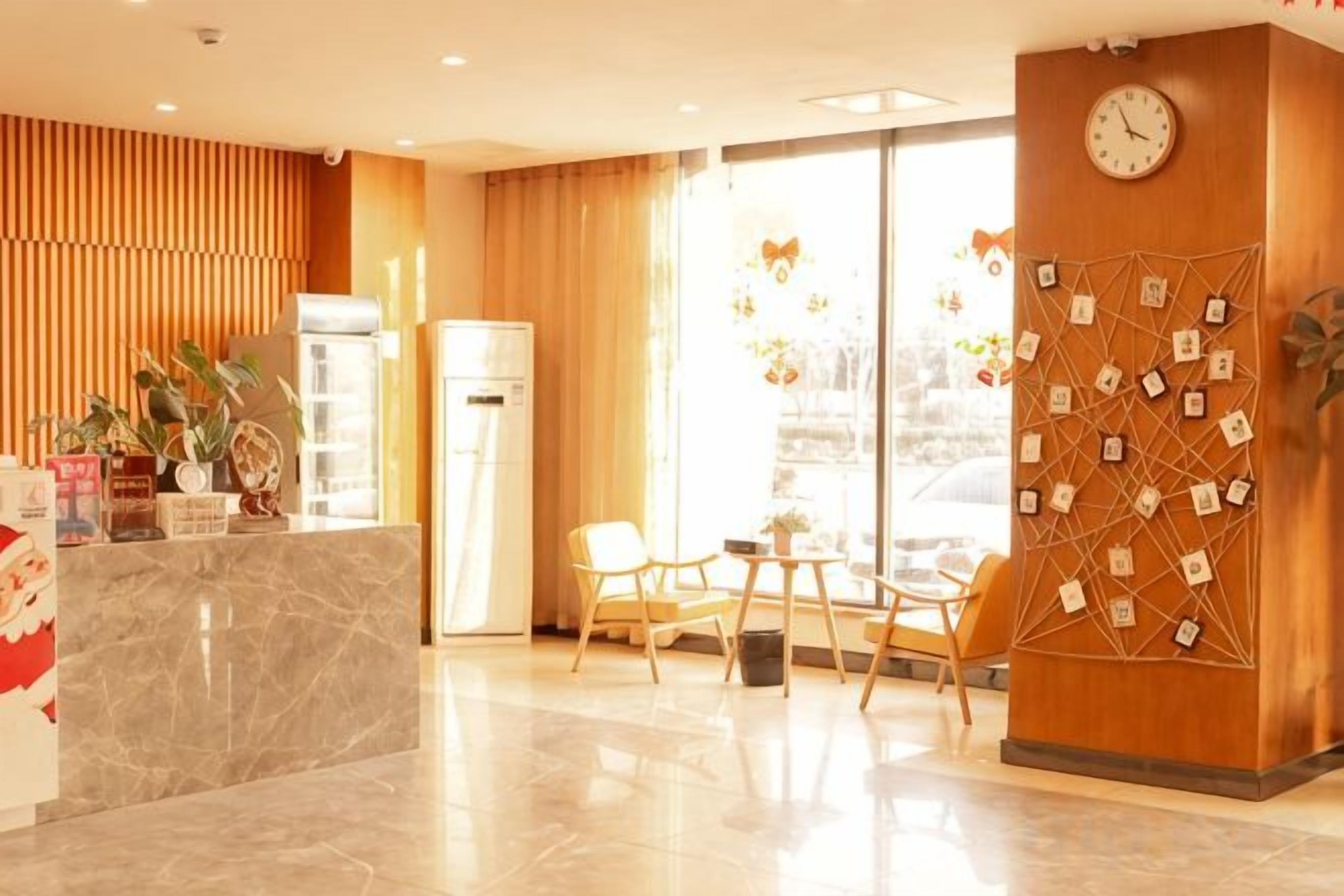 A hotel reception area with a marble counter, wooden paneling, a clock, and a wall decorated with small pictures.