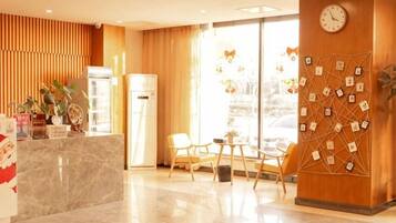 A hotel reception area with a marble counter, wooden paneling, a clock, and a wall decorated with small pictures.