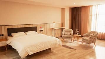 A hotel room with a large bed, two armchairs, a small table, and a nightstand.