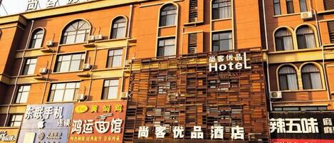 A hotel with a traditional facade, multiple windows, and signage for various businesses.