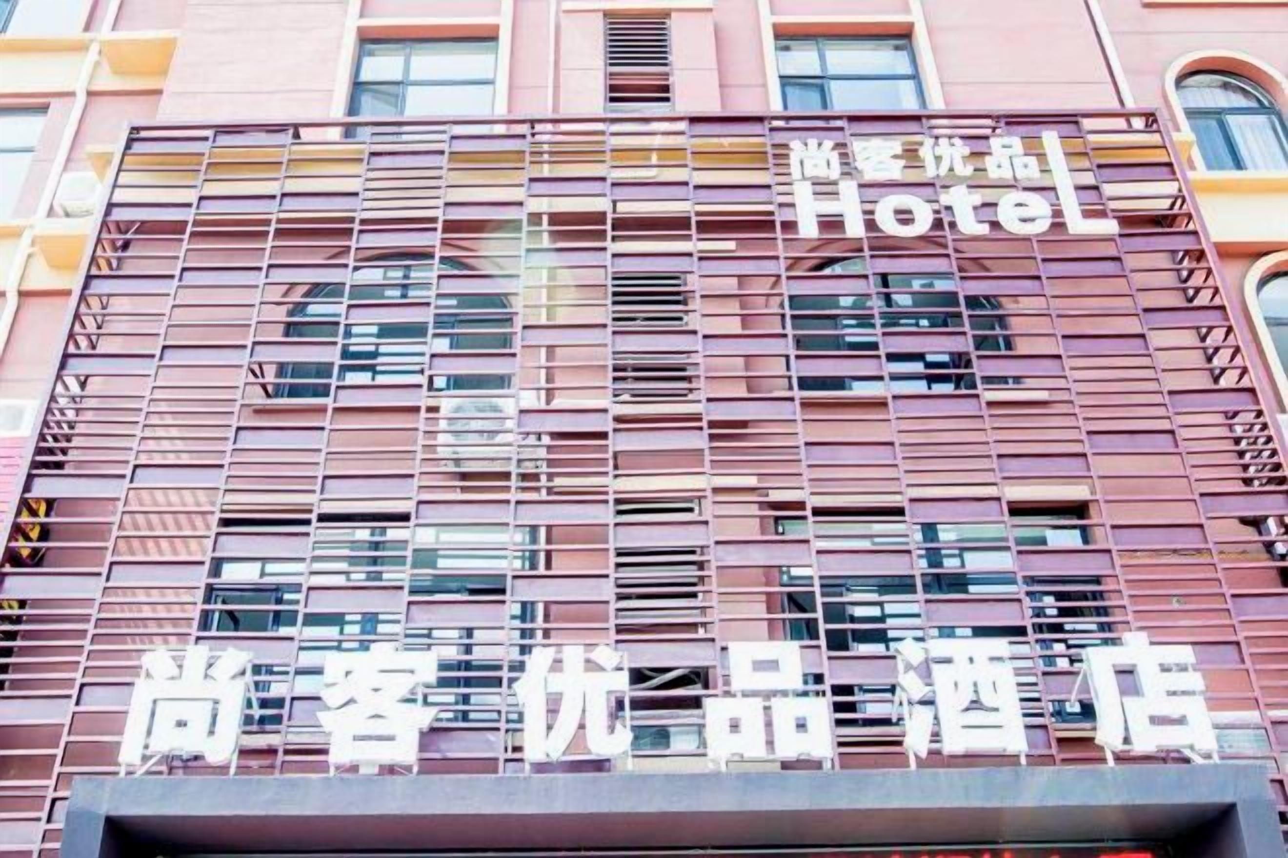 Fachada de hotel com padrão de janelas em grade e sinalização indicando ser um hotel.