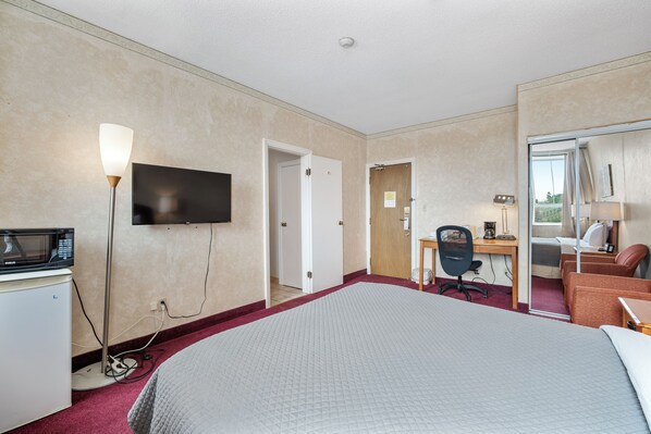 A hotel room with a large bed, a desk with a chair, a television, and a microwave. - Royal Inn and Suites at Guelph (Guelph)
