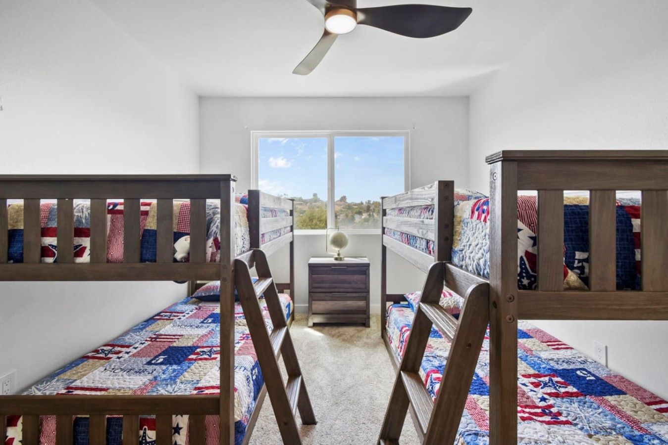 Una habitación con literas, una mesita pequeña y vistas por la ventana.