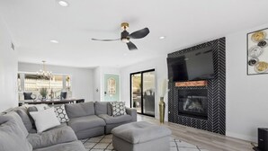 A modern living room with a sectional sofa, a fireplace, and a ceiling fan. - 5bed/3ba, Gameroom, Pool, Spa, Sleeps 20+, Views (San Diego)