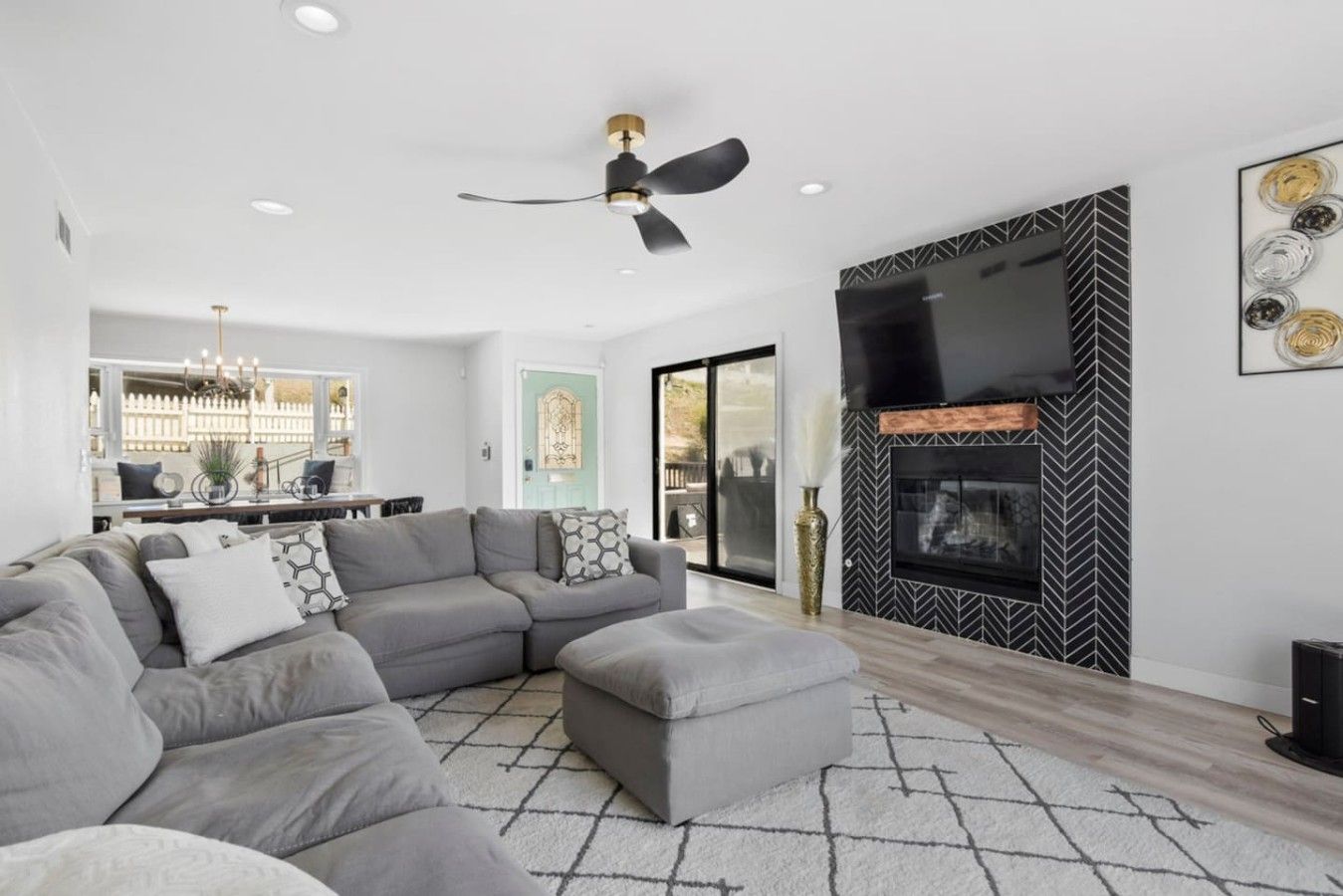 A modern living room with a sectional sofa, a fireplace, and a television mounted on the wall.