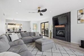 A modern living room with a sectional sofa, a fireplace, and a television mounted on the wall. - 3bed/2ba, Fam Friendly, Views & Downtown (San Diego)