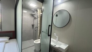 Ein modernes Badezimmer mit Glastrennwand, Toilette, Waschbecken und Spiegel.
