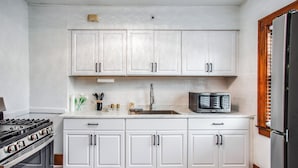A kitchen with white cabinets, a stainless steel stove, a microwave, and a refrigerator.