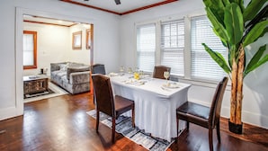A dining area with a table set for four, wooden chairs, a ceiling fan, and a large plant.