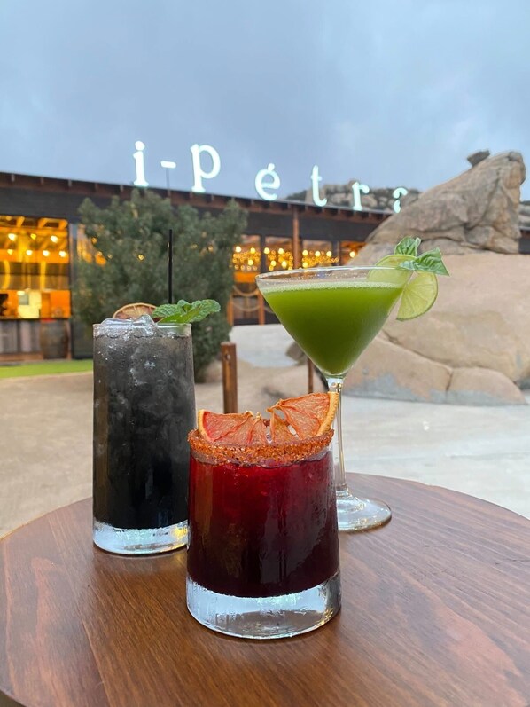 Three cocktails on a wooden table with a building in the background.