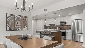 A modern kitchen with stainless steel appliances, a wooden dining table, and a central island. - New Top Floor 3Bed/2Bath, sleeps 8. Outdoor pool and Hot Tub Open Year Round! (Dead Man's Flats)