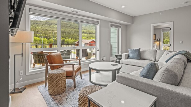 A modern living room with a large window, a sofa, a round coffee table, and a chair. - New Top Floor 3Bed/2Bath, sleeps 8. Outdoor pool and Hot Tub Open Year Round! (Dead Man's Flats)