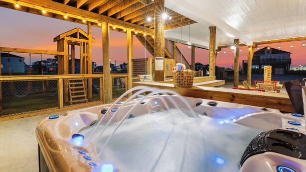 Un espace extérieur aménagé avec un bain à remous en bois, offrant une vue sur la ville au coucher du soleil.
