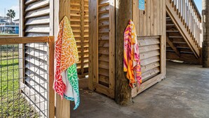 Une structure en bois dotée d’un escalier et d’une zone délimitée par une clôture, où sont suspendues des serviettes aux couleurs vives.