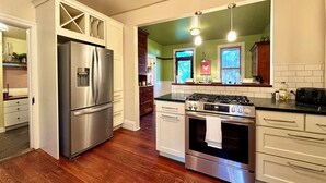 A modern kitchen with stainless steel appliances, wooden cabinets, and a green accent wall. - 2,200 Sq Ft w/ 2 Gamerooms, Firepit & Grill 15 Minutes To Hershey (Palmyra)