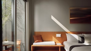 Un dormitorio moderno con cabecera de madera, una mesita de noche y un ventanal grande.