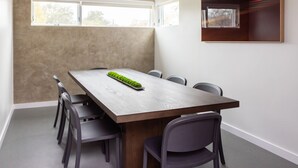 Un salón de conferencias con una larga mesa, seis sillas y un ventilador de techo.