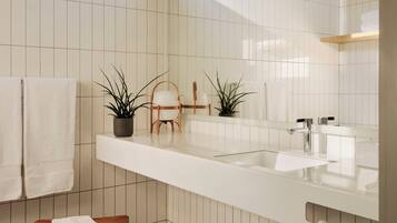 Een moderne badkamer met een grote spiegel, witte tegels, een houten bankje en twee potplanten.
