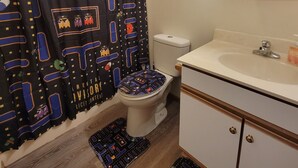 A bathroom with a toilet, sink, and mirror. There is a shower curtain with a space-themed pattern. - RiverTown Retro | King Bed | Near Deaconess | Pet-Friendly (Newburgh)